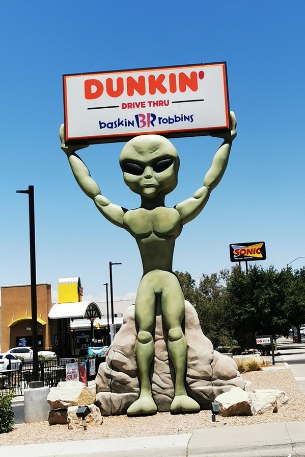 A large green alien holding a sign for Dunkin Donuts and Baskin Robbins in Roswell, New Mexico
